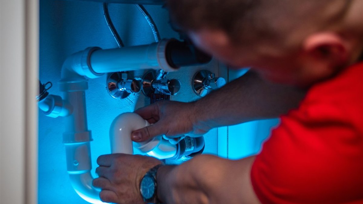 Plumber working on under-sink pipework